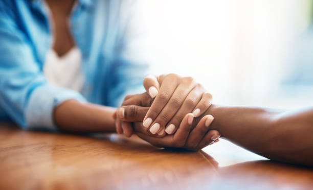 Closeup shot of two unrecognizable people holding hands in comfort at home